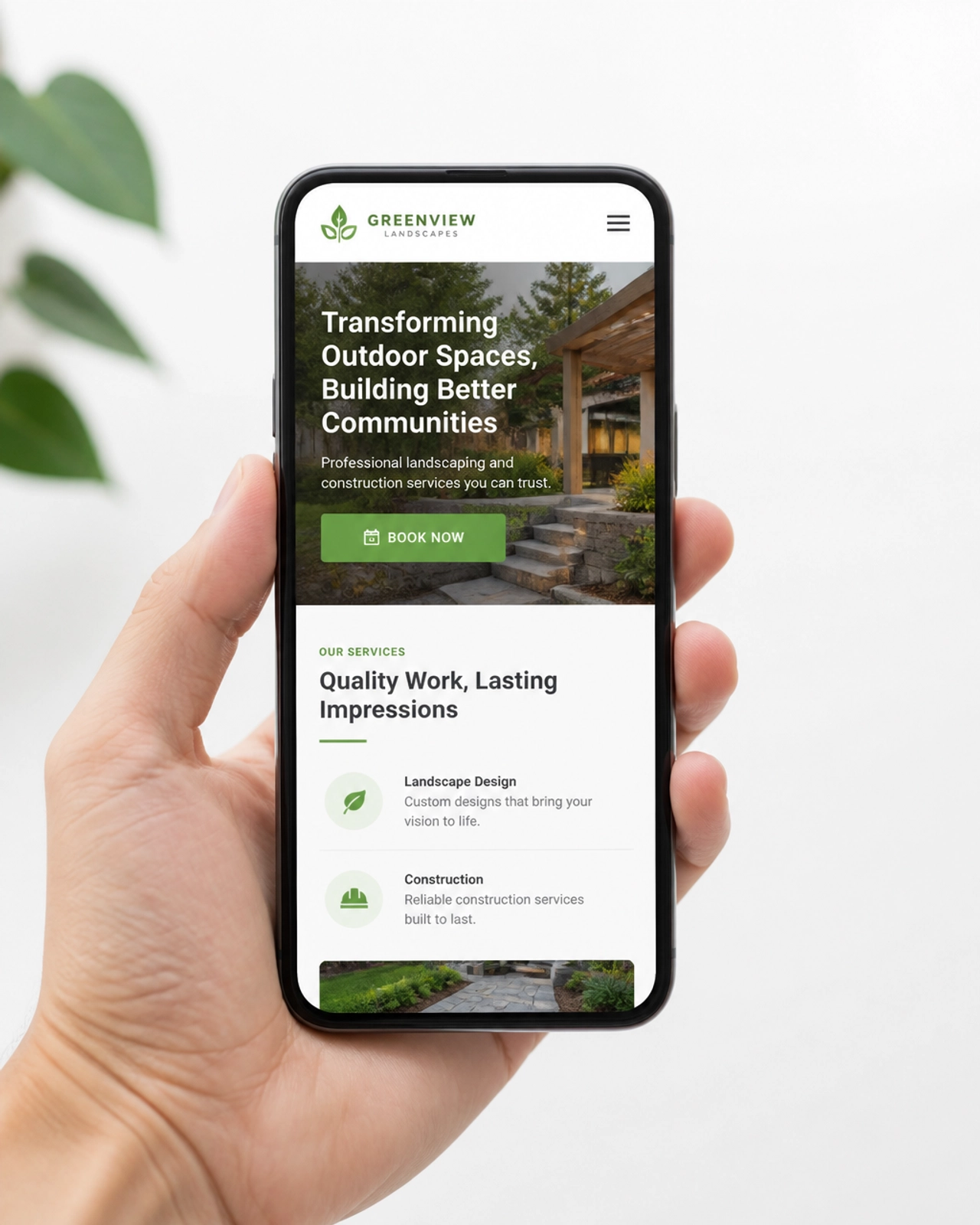 A high-quality photo of a smartphone displaying a responsive local business website with a clear green 'Book Now' button