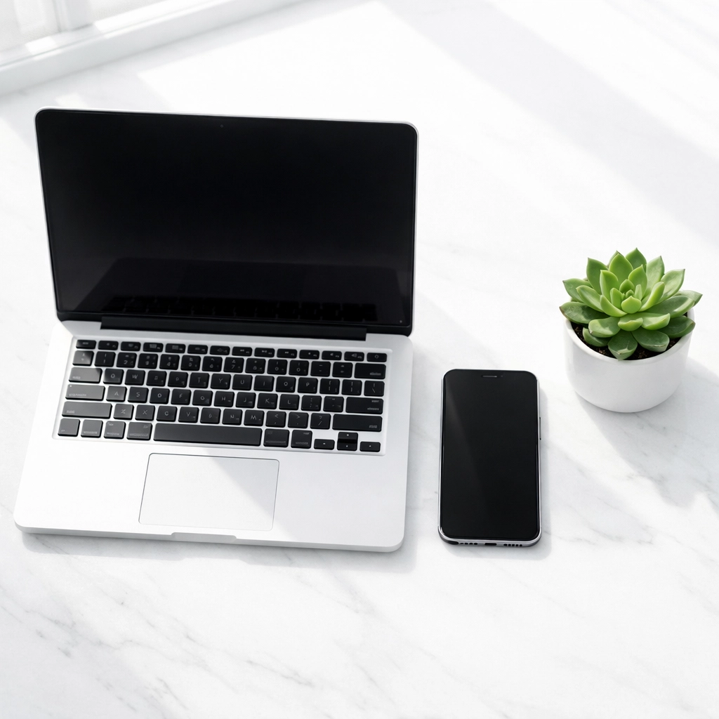 Modern laptop and smartphone on a white desk illustrating consistent business contact info for local SEO.