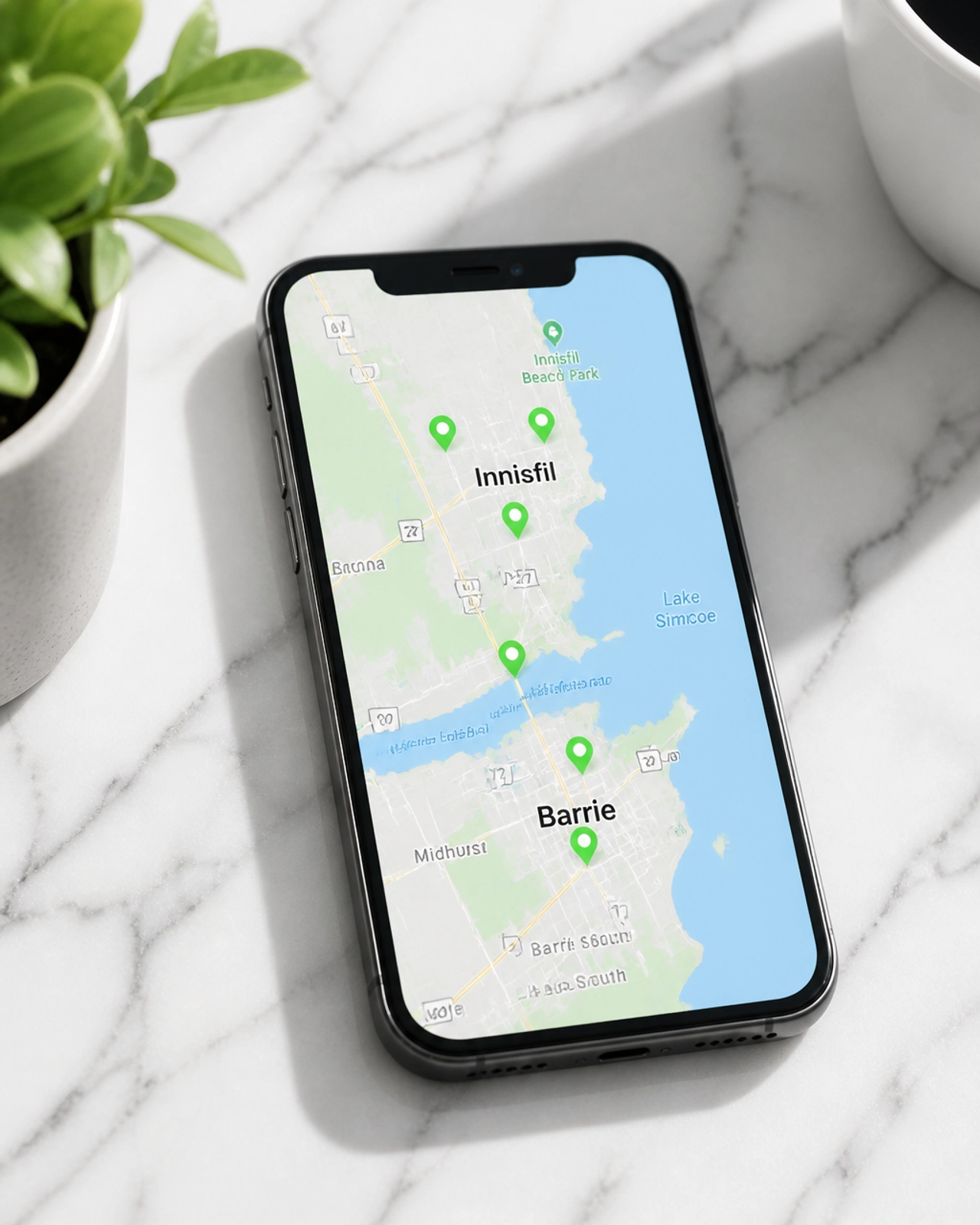 A modern smartphone showing a local map of Innisfil and Barrie, Ontario, with several glowing green location markers.